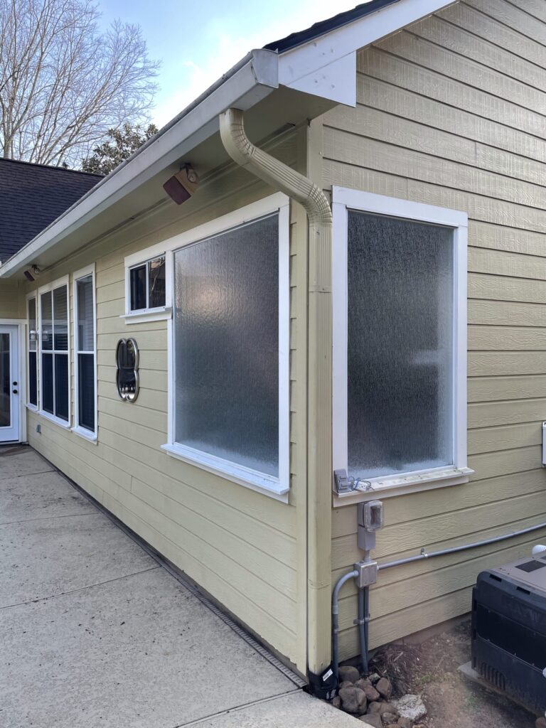 Champion Forest Exteriors expert inspecting worn and damaged siding on a residential home to assess if replacement is needed.
